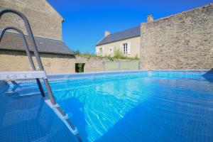 a swimming pool with a ladder in front of a building at LA FERME DE LONGUES maisons spécialisées pour les familles avec jeunes enfants in Longues-sur-Mer
