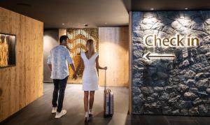 アルペ・ディ・シウージにあるHotel Rosa Eco Alpine Spaのスーツケースを持って廊下を歩く男女 +48枚の写真