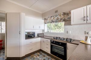 Una cocina con gabinetes blancos y un horno de estufa. en 19 Hill Street, en Plettenberg Bay 7 fotos más