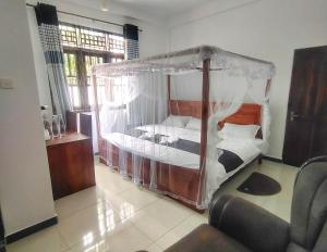 a bedroom with a canopy bed and a chair at The White House Resort in Wellawaya +43 photos