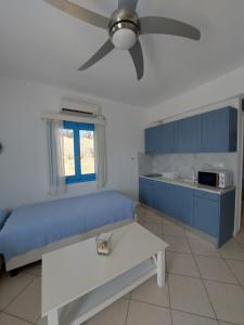 a living room with a blue couch and a ceiling fan at Milithos Apartments 1 in Adamantas +2 photos