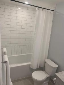 a bathroom with a toilet and a bathtub with a shower curtain at Beachview getaway at the New Carlyle 304 on the Main strip in Grand Bend in Grand Bend +11 photos