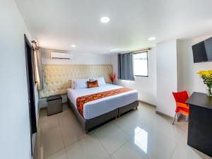 a bedroom with a bed and a red chair in it at Hotel Caribe Plaza Barranquilla in Barranquilla