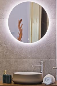 un bagno con specchio rotondo sopra un lavandino di Myrthea Luxury Villas a Karpathos Altre 24 foto