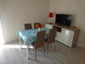 a dining room with a table with chairs and a television at Domus Anna in Montegrotto Terme +18 photos