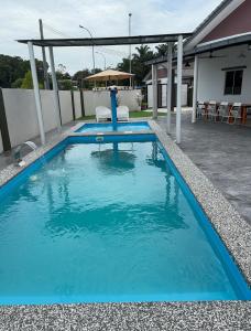 a pool with blue water in a yard at LaRinDa Teluk Kemang Private Pool - Islamic in Port Dickson