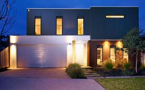 a house with a white garage door at night at Stylish Living- Fireplace, WiFi, Linen, 4 bdrm, Beach 850m in Inverloch