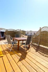a wooden deck with a table and chairs on a roof at Ferienwohnug Strandflieder in Borkum +9 photos