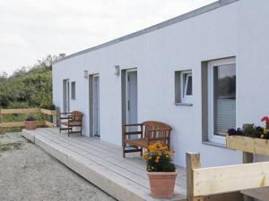 un porche de una casa blanca con bancos y flores en Ferienwohnung Möwe, en Borkum