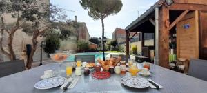 a table with a breakfast of bread and orange juice at La pause sous le pin B&B Chambres d'hôtes in Capestang