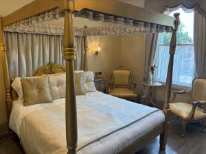 1 dormitorio con 1 cama con dosel y 2 sillas en canterbury lodge, en Kent