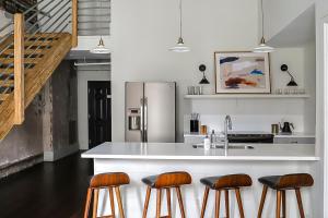 a kitchen with a counter with stools and a refrigerator at The Grant by Black Swan in Savannah