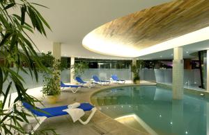 una piscina en un edificio con sillas azules en Hermitage Hotel en Mar del Plata