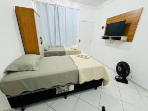 a bedroom with a bed and a flat screen tv at Kitnet cheia de estilo, ipatinga mg in Ipatinga
