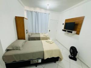 a bedroom with two beds and a flat screen tv at Kitnet cheia de estilo, ipatinga mg in Ipatinga