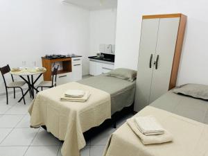 a bedroom with two beds and a kitchen with a table at Kitnet cheia de estilo, ipatinga mg in Ipatinga +3 photos