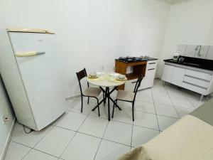 a kitchen with a table and chairs and a refrigerator at Kitnet cheia de estilo, ipatinga mg in Ipatinga