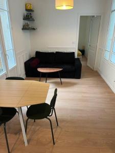 Una sala de estar con un sofá, una mesa y sillas. en New Cosy Home, en Nogent-sur-Marne