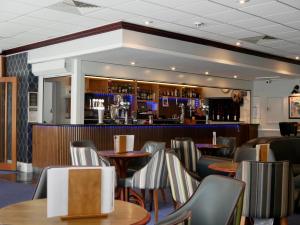 a restaurant with tables and chairs and a bar at Britannia Hotel Newcastle Airport in Newcastle upon Tyne
