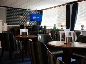 a waiting room with tables and chairs and a tv at Britannia Hotel Newcastle Airport in Newcastle upon Tyne