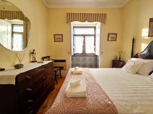 a bedroom with a large bed with a dresser and a mirror at Quinta da Malafaya in Nogueira