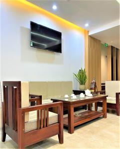 a living room with a table and a tv on a wall at Khách Sạn LUCIEN HOTEL Quy Nhơn in Quy Nhon