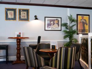 a waiting room with chairs and tables and posters on the wall at Britannia Hotel Newcastle Airport in Newcastle upon Tyne