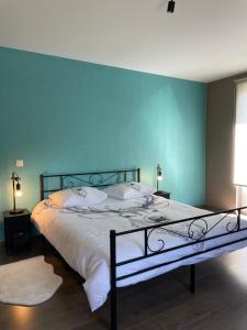 a bedroom with a large bed with a blue wall at Le Daguet in Florenville