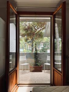 an open glass door to a patio with two chairs at Un Nido nel Verde in Cervia