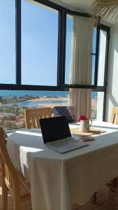 a laptop sitting on a table in a room with windows at Appartement Coucher de Soleil uniquement les familles in Oualidia