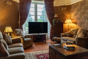 a living room with two couches and a flat screen tv at Killean Farmhouse B&B in Inveraray