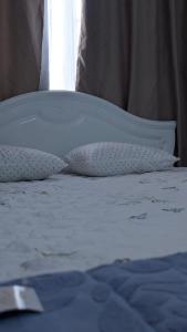 a bed with white sheets and pillows and a window at Койгельды 163 in Taraz
