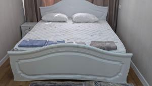 a white bed with two pillows on top of it at Койгельды 163 in Taraz