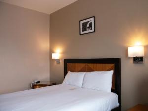 a bedroom with a white bed with two lights on the wall at Britannia Hotel Newcastle Airport in Newcastle upon Tyne