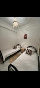 a bedroom with two beds and a chandelier at Appart Entier Chic à petit prix avec wifi in Oulad Tayeb