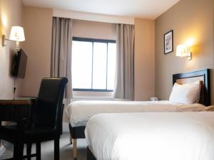 a hotel room with two beds and a desk and a window at Britannia Hotel Newcastle Airport in Newcastle upon Tyne