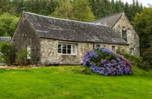 a stone house with flowers in front of it at Killean Farmhouse Cottages in Auchnangoul +104 photos
