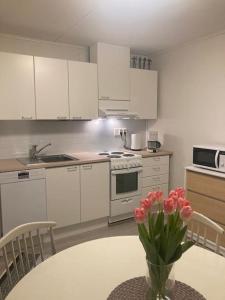 a kitchen with a table with a vase of pink flowers at Paritalon huoneisto in Raahe