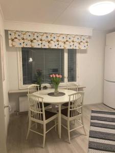 a kitchen with a table with chairs and a vase of flowers at Paritalon huoneisto in Raahe +3 photos