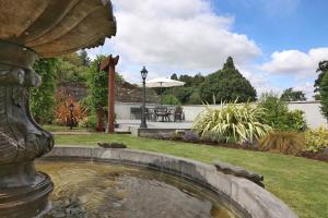 a pond in a yard with a table and an umbrella at Meadowside B&B in Bunclody