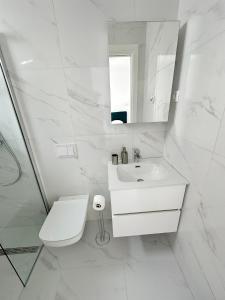 a white bathroom with a toilet and a sink at Beautiful new PalmTree Apartments in Vir +45 photos