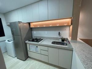 a small kitchen with a sink and a refrigerator at Apto de frente ao mar da Praia de Itaparica ES in Itaparica
