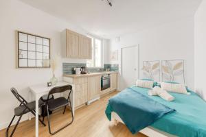 a bedroom with a bed and a desk and a kitchen at Le Clichy Chic in Clichy