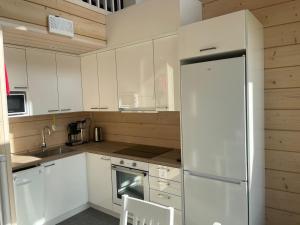 una cucina con mobili bianchi e un frigorifero bianco di Miilu Resort a Ylläsjärvi