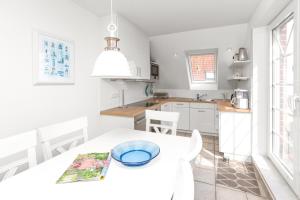 Una cocina blanca con una mesa y sillas blancas. en Residenz am Meer 24C Graugans, en Juist