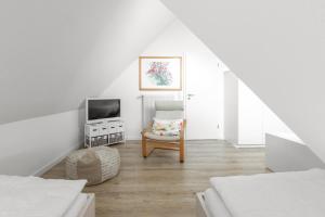 Habitación blanca con silla y TV en Residenz am Meer 24C Graugans, en Juist