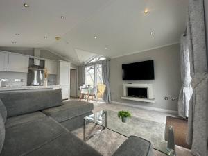 a living room with a couch and a tv at WH - Smugglers Lodge in Aberaeron