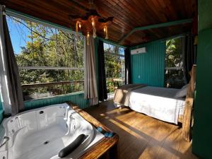 a bath tub in a room with a bed and windows at Pousada Vale de Luz FW in Frederico Westphalen +96 photos