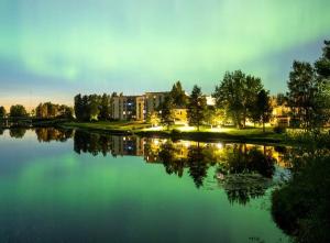 a reflection of a building in a lake at night at JK Apartment Jannela in Lapua