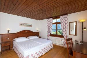 a bedroom with a bed and a desk and a window at Hôtel de Gruyères in Gruyères